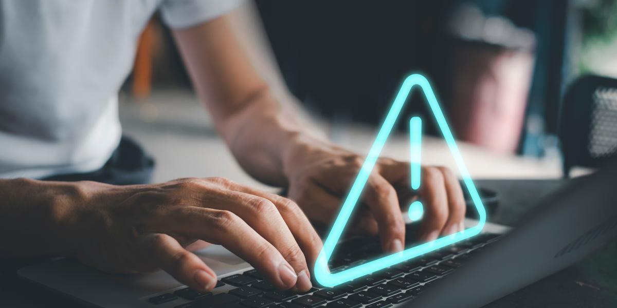 A blue triangle with an exclamation point above a keyboard.