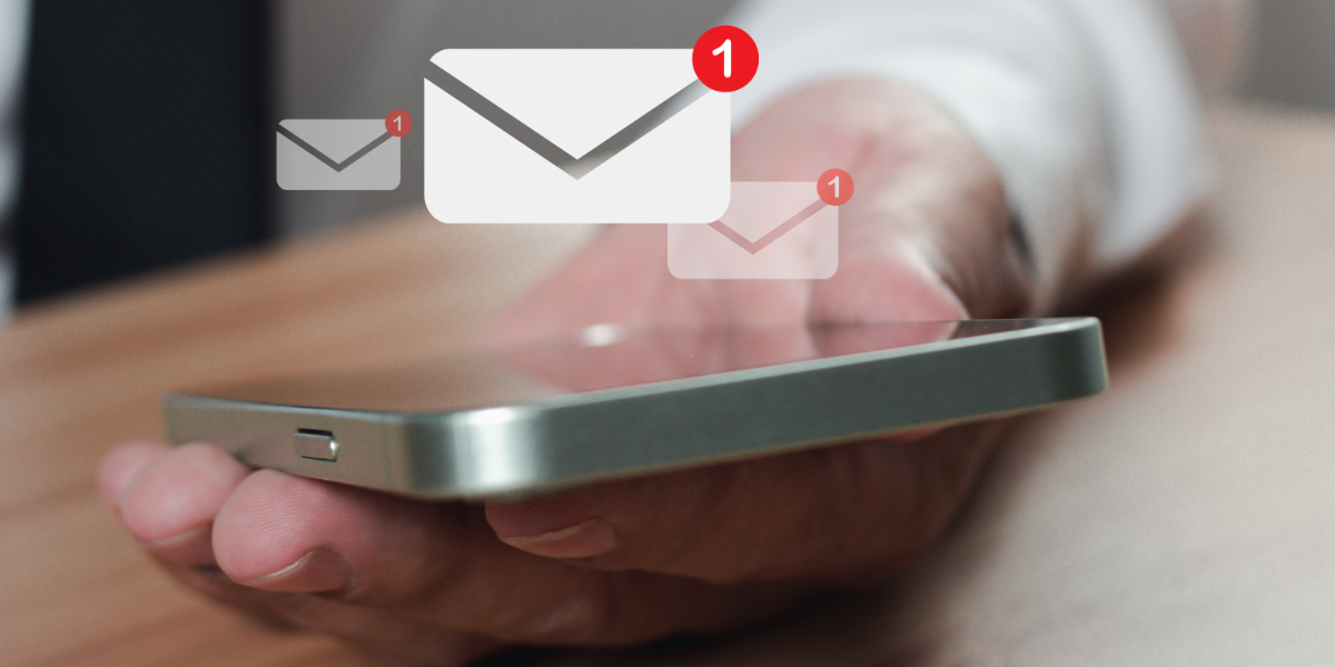 Business man holding mobile phone with floating email icon.