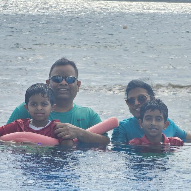 Marry, her husband, and their two sons swimming on a sunny day.