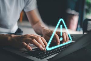 A blue triangle with an exclamation point above a keyboard.